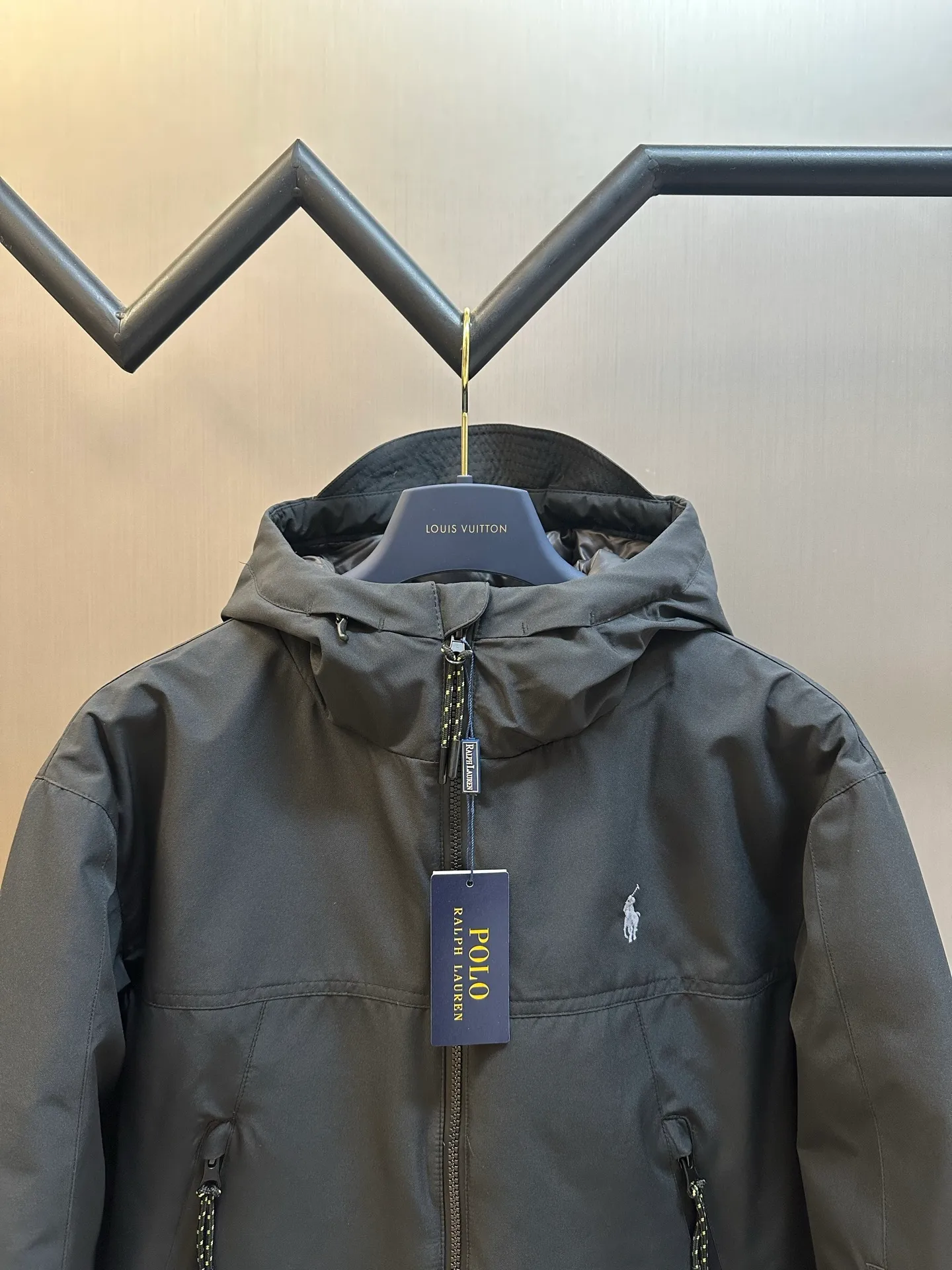 P970 Ralph Lauren logo hooded down jacket. The density of high-density nylon taffeta is about 210T-300T. The surface is smooth and slightly matte. It has excellent windproof and waterproof performance (with DWR water-repellent treatment). It has strong wrinkle resistance and is easy to care for. It is in line with the positioning of American casual "durable and practical".  The inner lining is made of 100% polyamide. The high-density and tight weaving process prevents fine lint from getting out of the gaps in the fabric. The smooth surface improves the putting on and taking off experience, and the excellent wear and tear resistance ensures damage caused by frequent use, while the light and soft texture does not affect the overall weight.  It uses 90 white duck down with a weight of 220g to ensure excellent thermal insulation performance. After strict screening and processing, the velvet is not easily drilled, ensuring durability. The classic jacket has a slightly loose fit, with slightly dropped shoulder lines (the shoulder width is 1-2cm wider than the standard fit). The length reaches the hips, and the sleeves are slightly tapered straight sleeves, taking into account freedom of movement and casual style.  The adjustable Velcro on the cuffs allows you to freely adjust the tightness according to the thickness of your wrist and personal preferences, effectively preventing cold wind from intruding, and improving the warmth performance. Two zippered pockets on the front are convenient for placing frequently used items, and the zipper design ensures that items are not easily lost. A built-in pocket on the left side of the chest provides a safe storage space for some small private items.  The drawstring design at the hem allows you to adjust the shape of the jacket according to your body shape and dressing needs. Whether it is loose and casual or slim and neat, you can easily control it.  Polo horse logo on the left chest: flat satin stitch embroidery (satin embroidery), using 100% polyester high color fastness embroidery thread (the color number is consistent with the brand's standard red color card), the stitch density is 12-15 stitches/cm, the outline of the horse logo is clear, and the details of the rider and horse are burr-free. Precise positioning through the template (12cm from the bottom of the collar and 8cm from the placket) ensures symmetry and centering.  size：s m l xl
